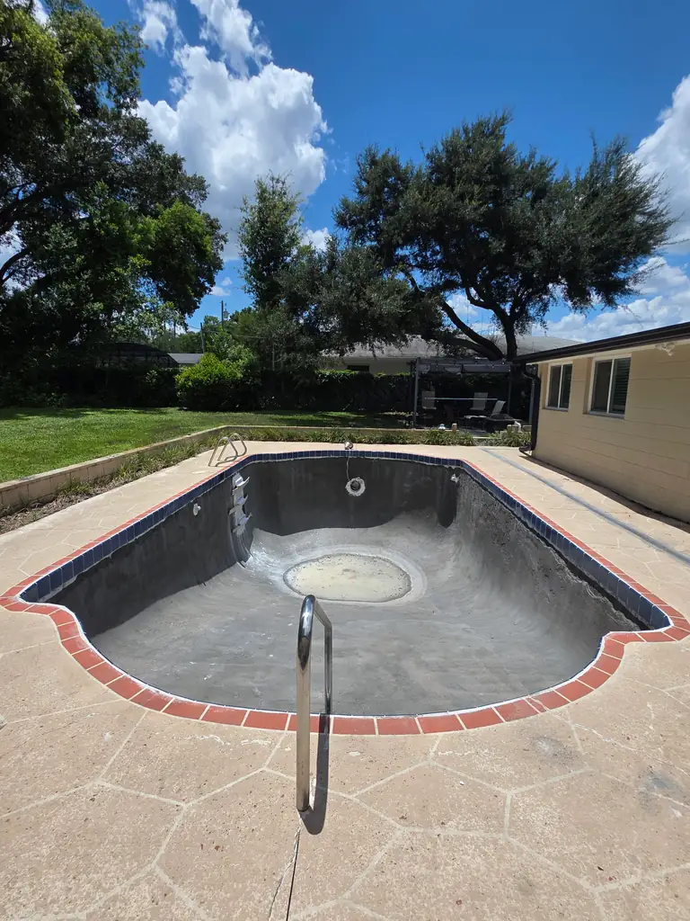 Drained residential swimming pool showing the dark existing interior before finish restoration.