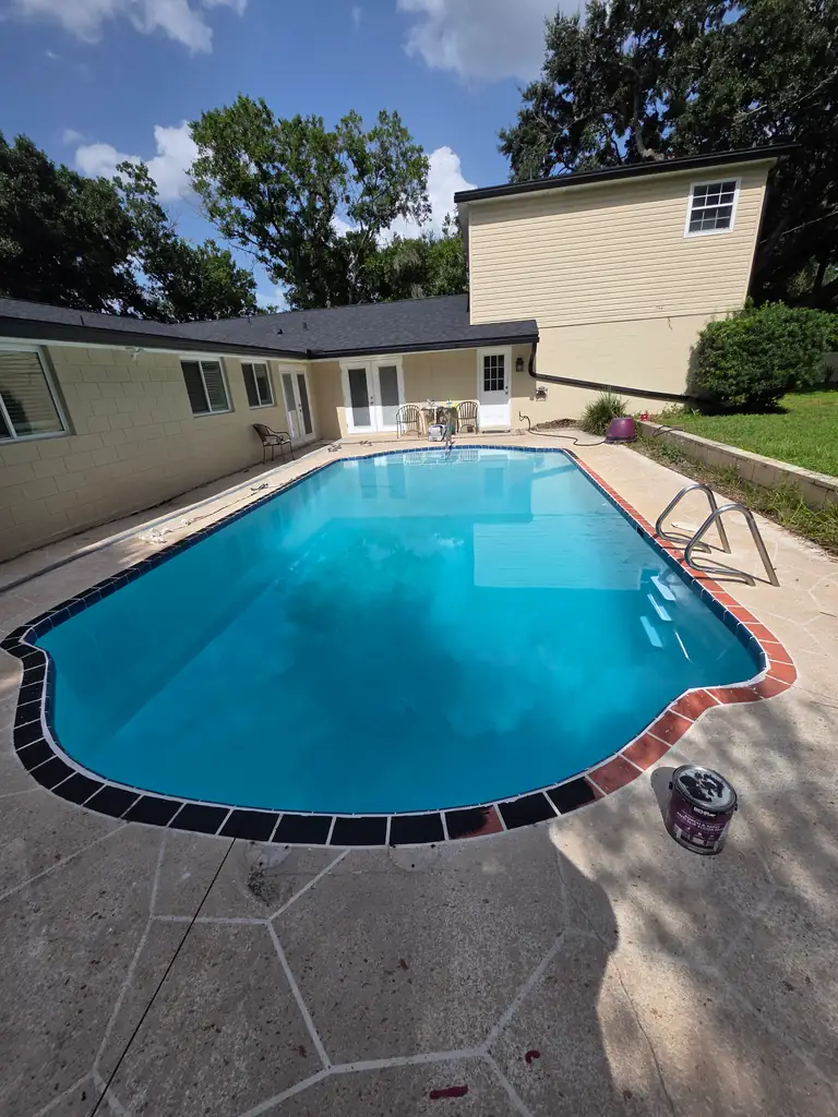 Same residential swimming pool refilled with the lighter interior visible while closeout materials remain on the deck.