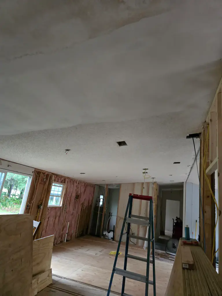 Interior ceiling compound, exposed framing, and a ladder during renovation