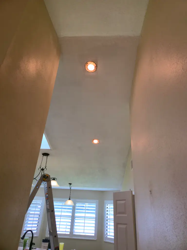 Hall and adjoining interior rooms during ceiling and wall work with a ladder visible.