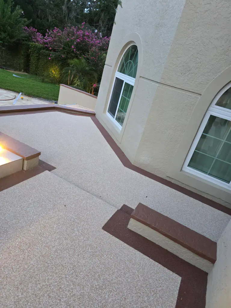 Close view of a dark accent border meeting the light-tan coated courtyard surface.